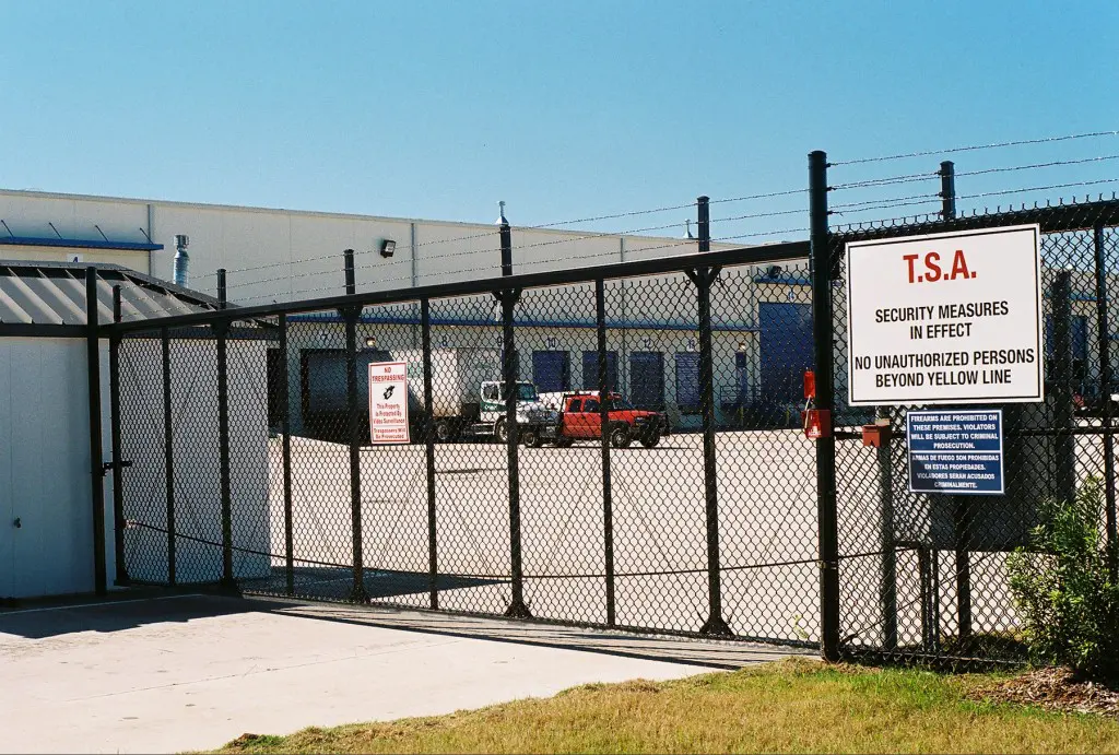 Industrial cantilever slide gate with TSA security signage at a freight facility perimeter