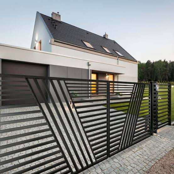 Modern black slatted residential driveway gate with a contemporary home behind it